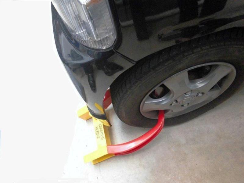 黒色の車の左前のタイヤにタイヤロックがかけられている写真