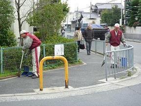 大阪トヨタLOGI&B-TEC株式会社の社員たちが歩道のごみを箒で集めている様子の写真