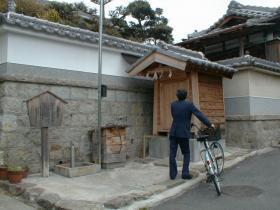 井戸屋形の大蛇の井戸を自転車を降りた人が見ている写真