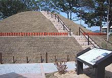 丘陵上にある太秦高塚古墳と手前に説明看板が映っている写真