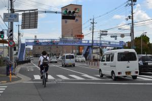 あちこちに信号機が設置され自動車が走行しており、道路の上に横断歩道橋がある現在の写真