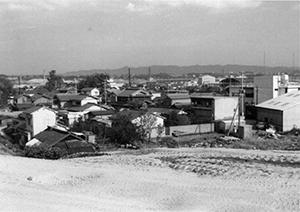 堤防から住宅街に降りていく道がカーブしながら下の方に向かって続いている昔の白黒写真