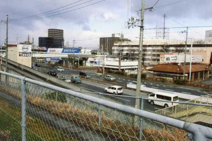 二車線の道路を車が走っており、後方には大きなマンションや商業施設などが建っている現在の緑町の写真