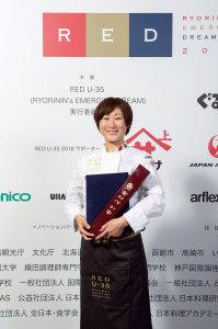 賞状ホルダーなどを持ち笑顔で写っている山本さんの写真