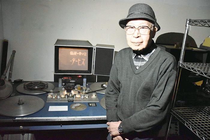 小さなモニターや機材があり、機材の横に立っている渡辺泰さんの写真