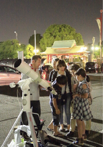 向井さんの望遠鏡の周りに集まってレンズをのぞき込んでいる子供と大人の写真