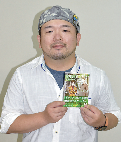 両手で小説本を持っている最東対地さんの写真