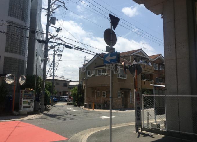 市道が通っており、道路沿いにはカーブミラーや標識が設置され住宅が立ち並んでいる現在の写真