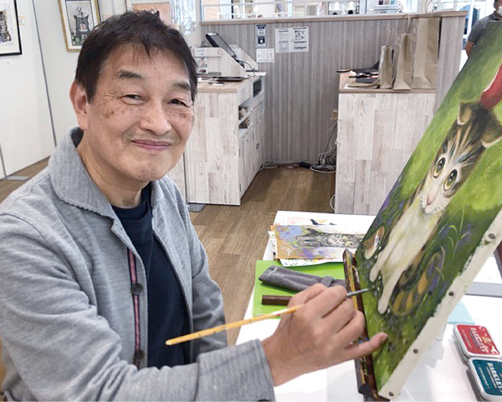 キャンパスに猫の絵を描いている勝間としをさんの写真