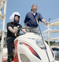 おにぎりのかぶり物を着け、農家を訪れた米田さん(左)