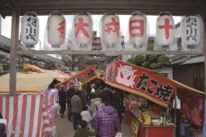 ねや川十日戎祭りの提灯とたこ焼きやたい焼きの出店が並ぶ参道に多くの人が訪れている写真