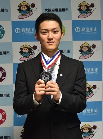 首から下げたメダルを両手で持っている森井涼太さんの写真