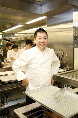 白衣を着て調理場に立っている山根さんの写真