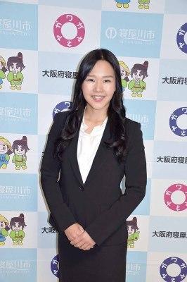 両手を組み微笑んでいるスーツ姿の藤田真実さんの写真