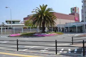 ロータリーの真ん中に大きな木が1本と草花が植えられており、後方には百貨店が建っている写真