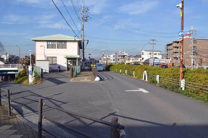 白い壁に2階建ての市立消費生活センターの横に歩道と奥には橋が見える今の写真