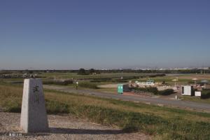 「淀川」と文字の彫られた石碑の先に見える淀川河川公園の写真