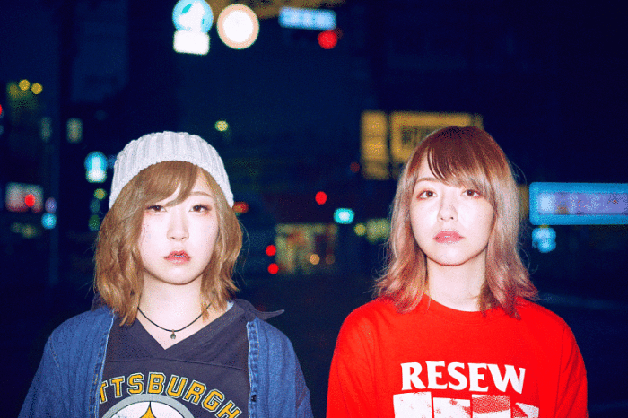 白いニット帽に青い服を着た女性と赤い服を着たガールズロックバンド(yonige)2名の女性の写真