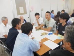 机に向かい、資料を見たりメモを取ったりしながら話し合いをしている参加者の写真