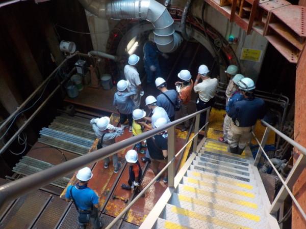 工事現場の中の空洞の手前の階段を下りたところで停まっている、白色のヘルメットを被った参加者の写真
