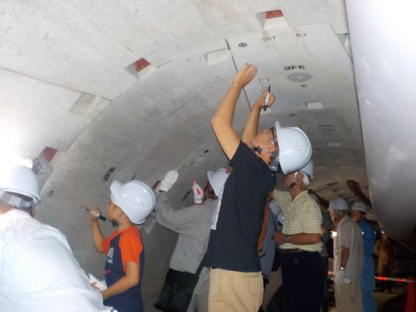 大きな空洞の天井に、白色のヘルメットを被った参加者たちがそれぞれペンを持って書いている写真