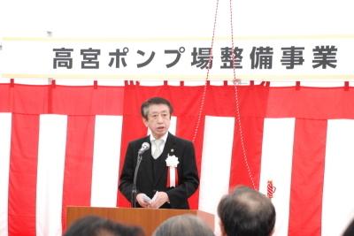 紅白幕の上に高宮ポンプ場整備事業と書かれた貼り紙の前の壇上で、北川市長がマイクの前で話をしている写真