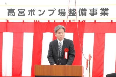 紅白幕の上に高宮ポンプ場整備事業と書かれた貼り紙の前の壇上で、竹内副知事が挨拶を行っている写真
