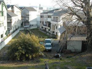 集合住宅の真ん中に大きな木がたちその横にトラックが停まっている整備前の茨田樋の写真