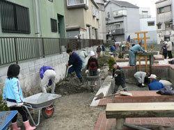 参加者全員で、水路の中のすくった土砂をスコップで集め台車で運んでいる作業の様子の写真