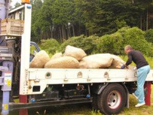 川岩をトラックの荷台に載せている男性の写真
