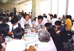 資料が並んだテーブルを囲み、熱のこもった議論をしている参加者の写真