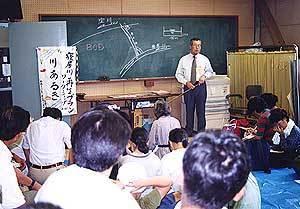 淀川と導水路、寝屋川の関連の説明をしているスーツ姿の男性と話を聞いている参加者の写真