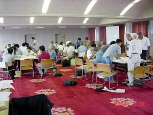 グループごとに分かれてテーブルに着いているワークショップの参加者が、熱心に話し合っている写真