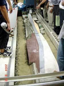 コンクリートブロックを横一列に並べた、大きくて横長の駅前親水河川空間の模型を参加者たちが見学している写真