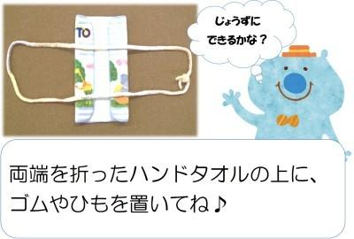 「じょうずにできるかな?」「両端を折ったハンドタオルの上に、ゴムやひもを置いてね」の文と、両端が折ってあるハンドタオルの上に紐が置いてある写真