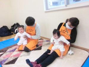 オレンジ色のエプロンをつけた応援リーダーの先生2人がそれぞれ赤ちゃんを抱っこしている写真
