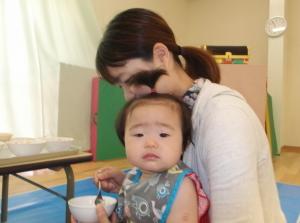 母親の膝の上で離乳食を食べている赤ちゃんの写真