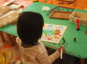 足形アートにペンで絵を描き加えている女の子の写真
