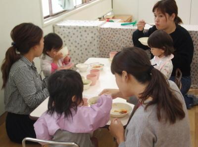 子供が食べるのを手伝いながら食事をしている母親の写真