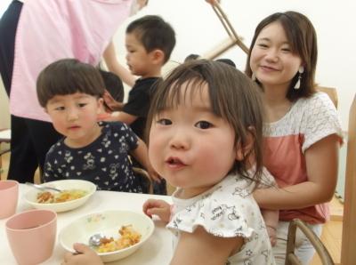 給食を食べている男の子、食べている途中でカメラのほうを振り向いた女の子、赤ちゃんを抱いている母親の写真