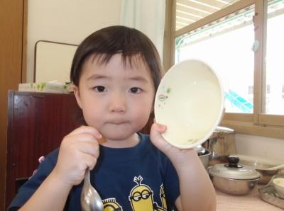 左手に空になったお皿、右手にスプーンを持っている男の子の写真