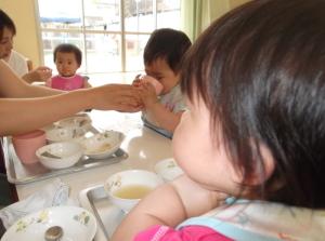 離乳食を食べている子供とコップでお茶を飲んでいる子供の写真
