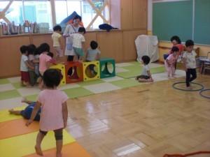 ゲームボックスにチャレンジしている子どもと支えている先生、順番を待って並んでいる子ども達、マットやフープの和の上を歩いている子どもの写真