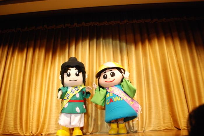 ねや丸くんと、はちかづきちゃんが並んで舞台の上に立っている写真