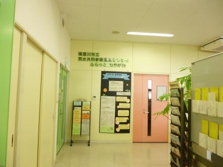 壁側に設置されたパンフレットスタンドに沢山の資料が置いてあり、ピンク色の片開きドアを正面に見た写真