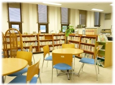 丸テーブルと椅子がセットされており、棚に沢山の本が並んでいる写真