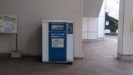 建物横に設置されている中央が青で淵が白い長方形の返却ポストの写真