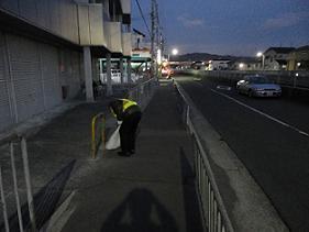 歩道脇のごみを拾うダイトタクシーの社員の写真