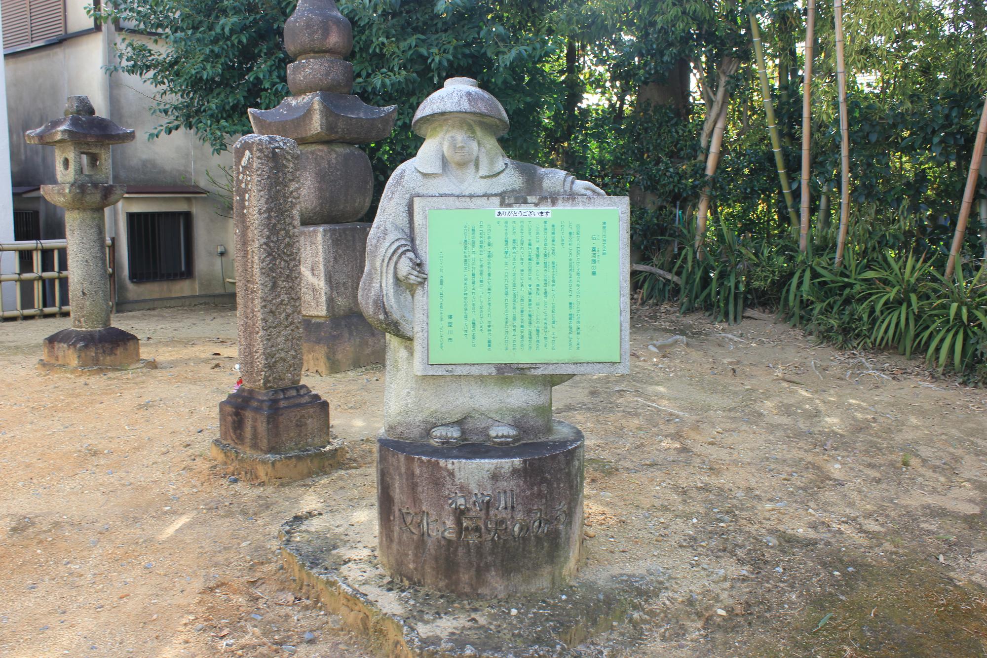 秦河勝の墓と伝わる場所に立つ五輪塔と灯篭の横の鉢かづき像