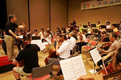 指揮者に合わせてバイオリン、チェロなど楽器を演奏する寝屋川市民管弦楽団の写真